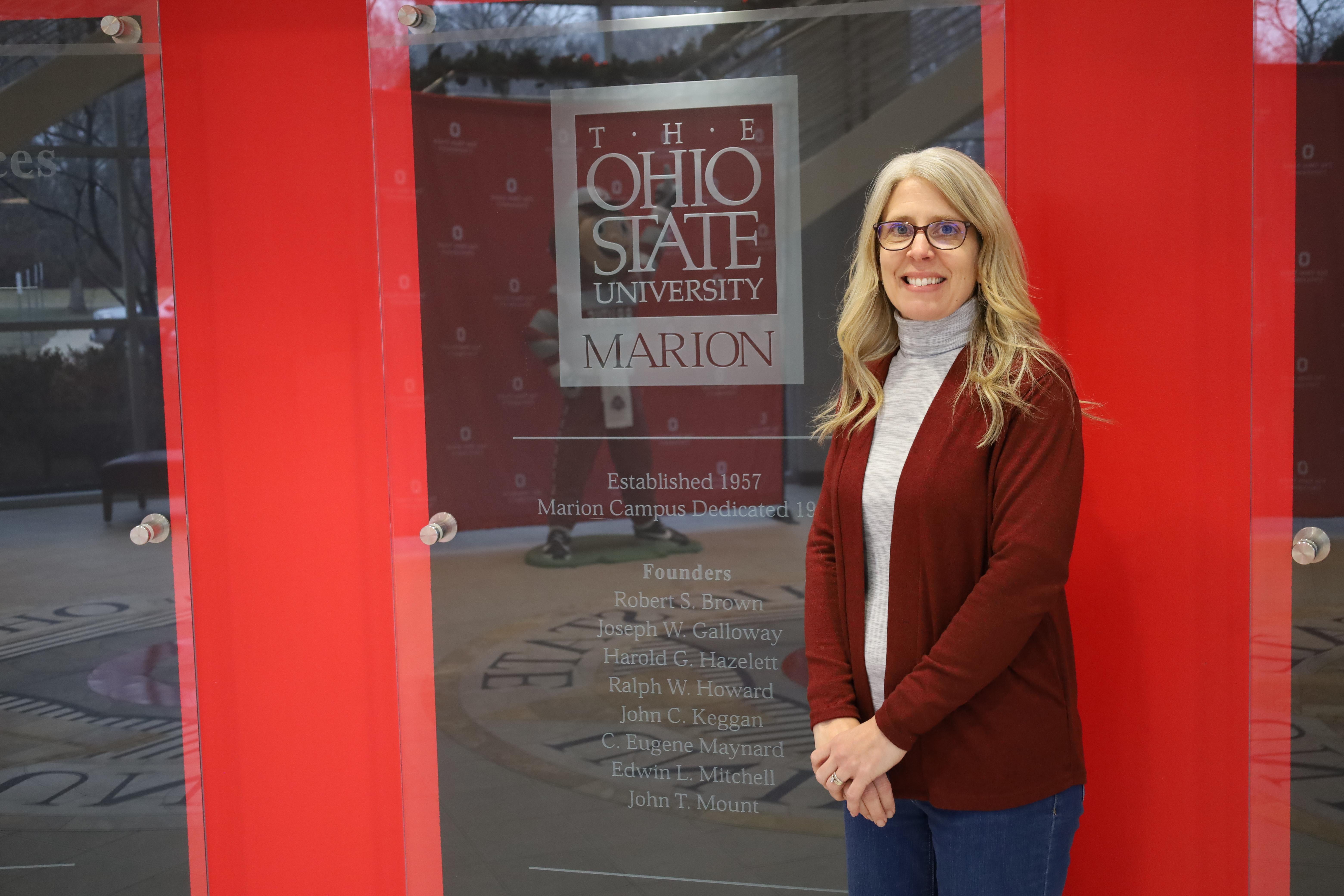 Woman in front of glass display honoring building founders