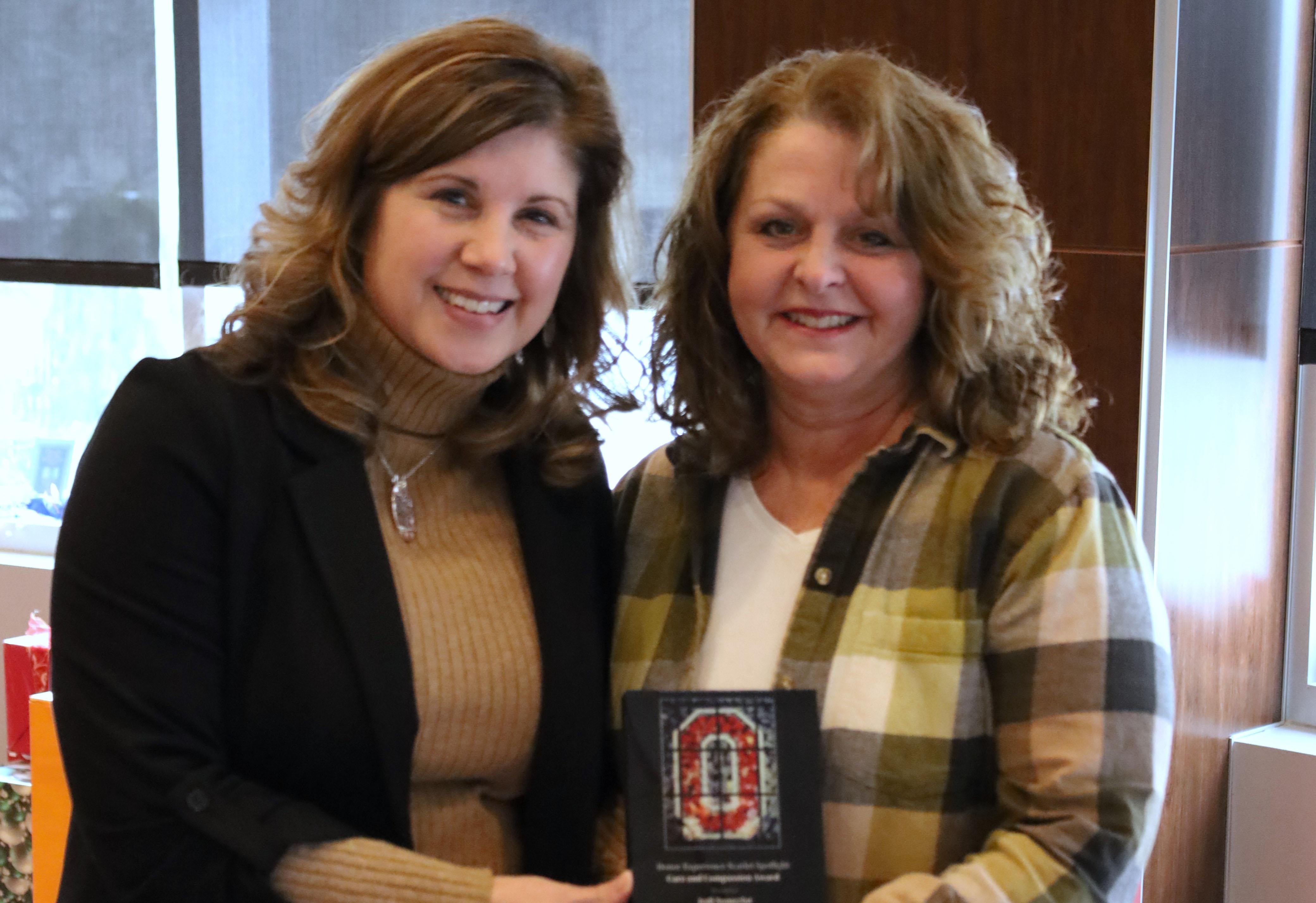 two women holding plaque