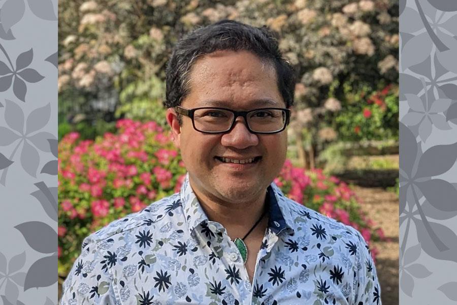 man in print shirt and glasses in front of flower garden