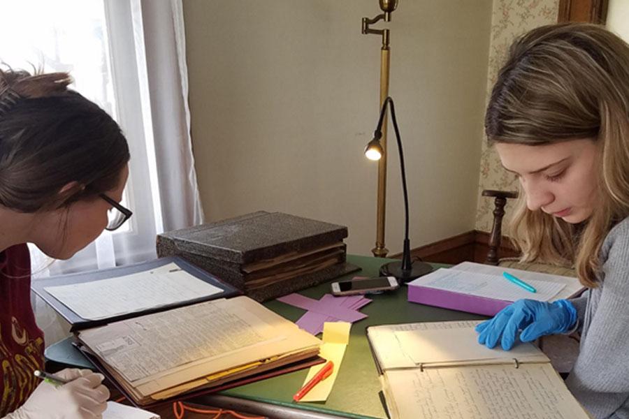 two young women review old archive information from women's club home