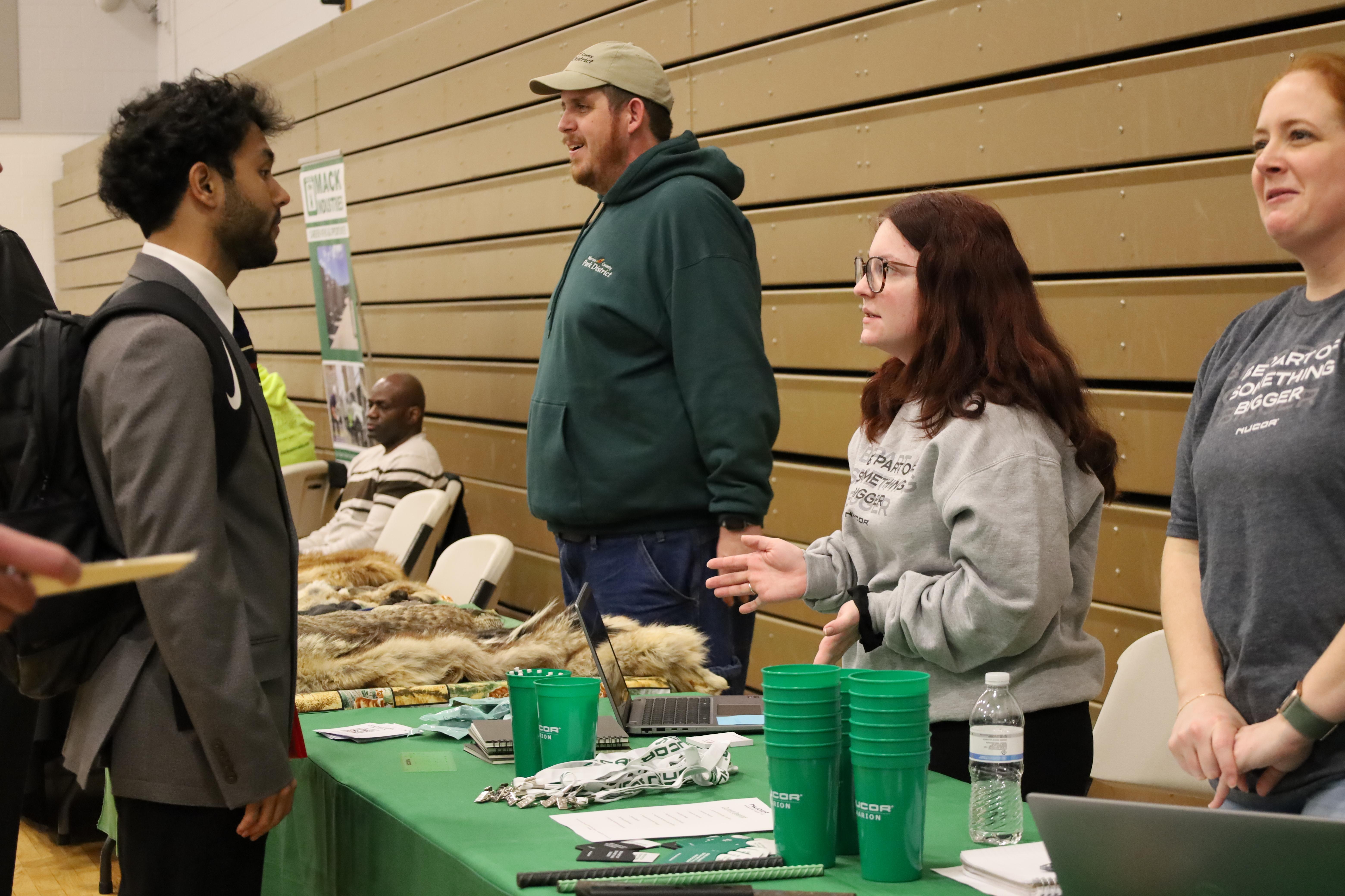 man in suit speaking with potential employer at job fair