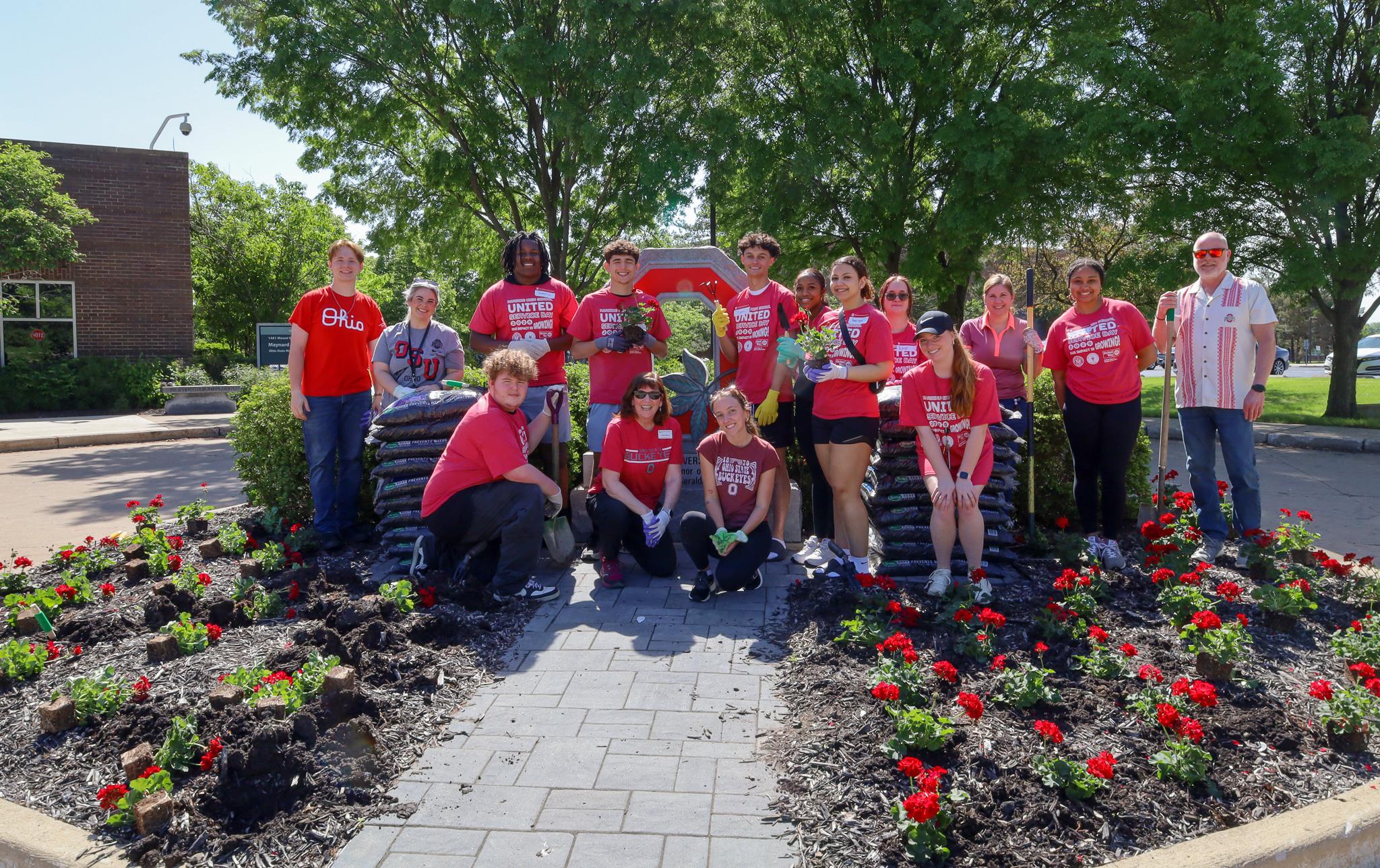 group planting flowers in front of granite block O