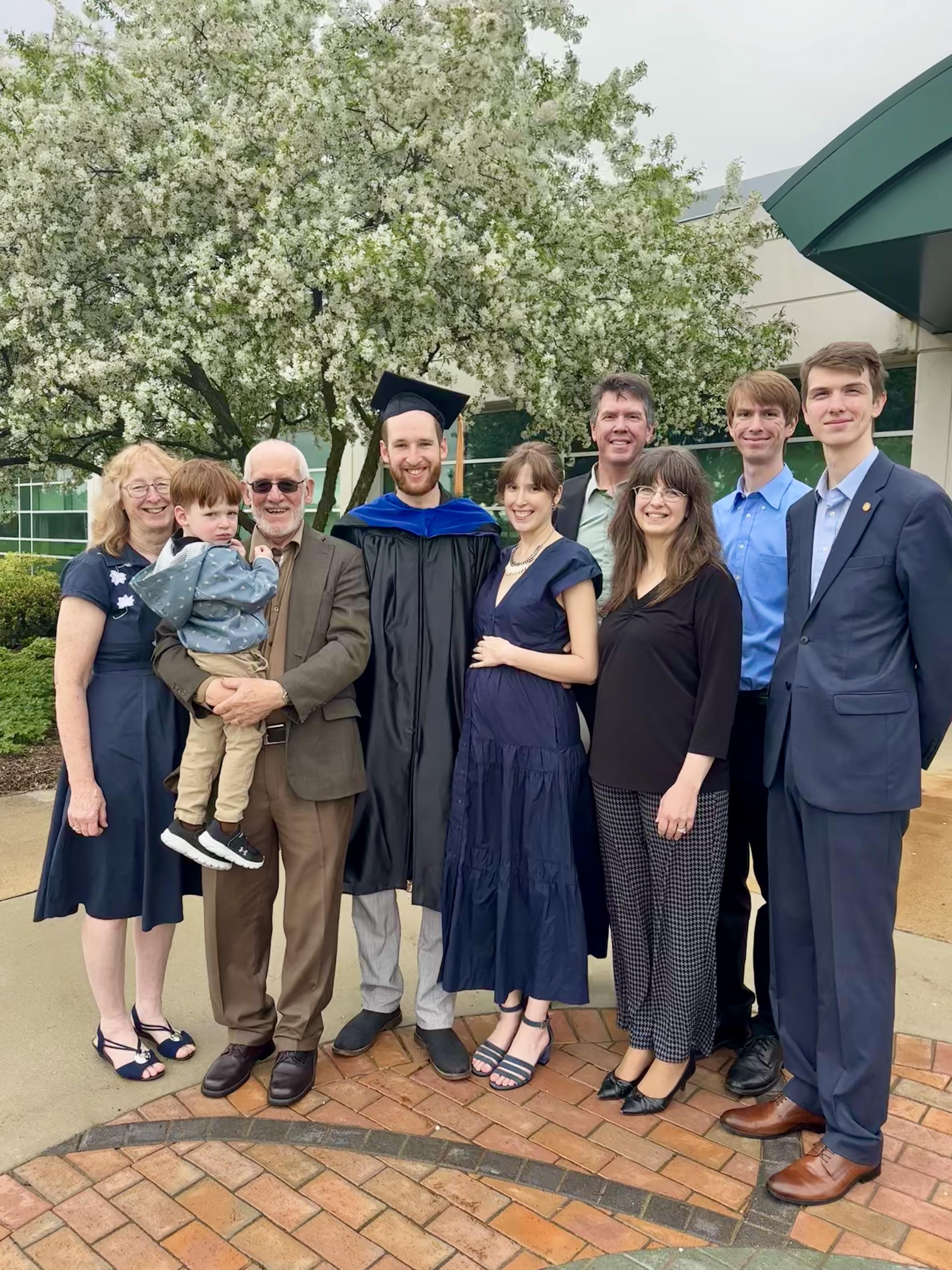 Group outdoors with college graduate in cap and gown