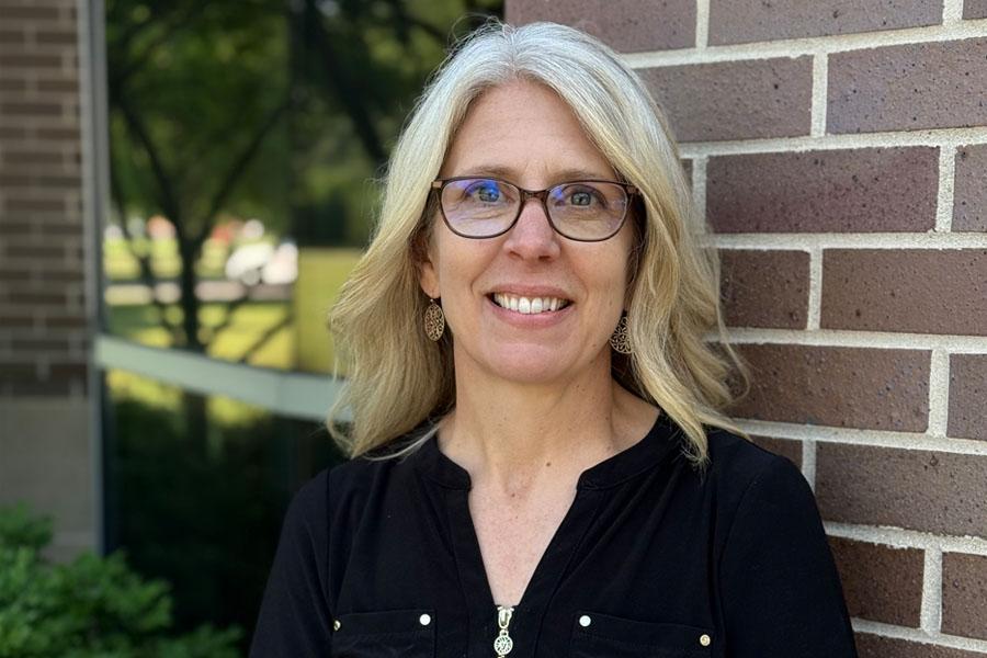 woman in glasses in front of brick building