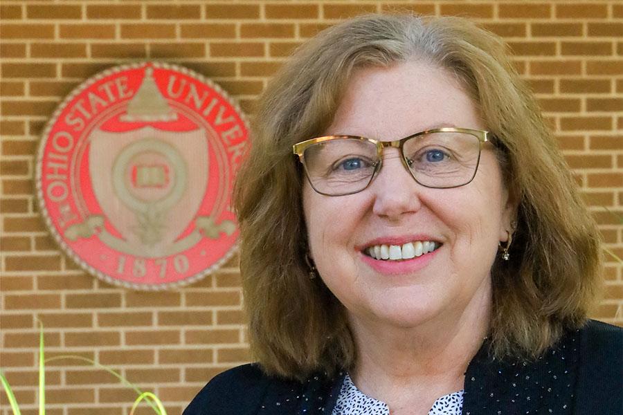 woman smiling with building and university seal in background