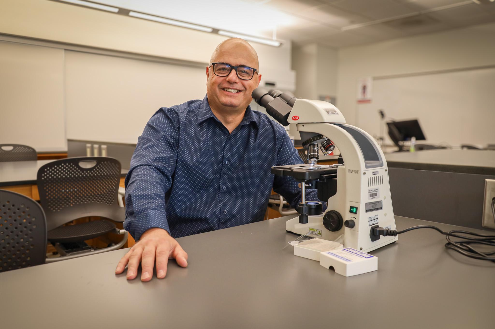man in lab behind microscope