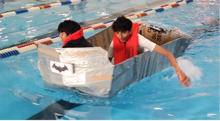 middle schoolers floating in a cardboard boat