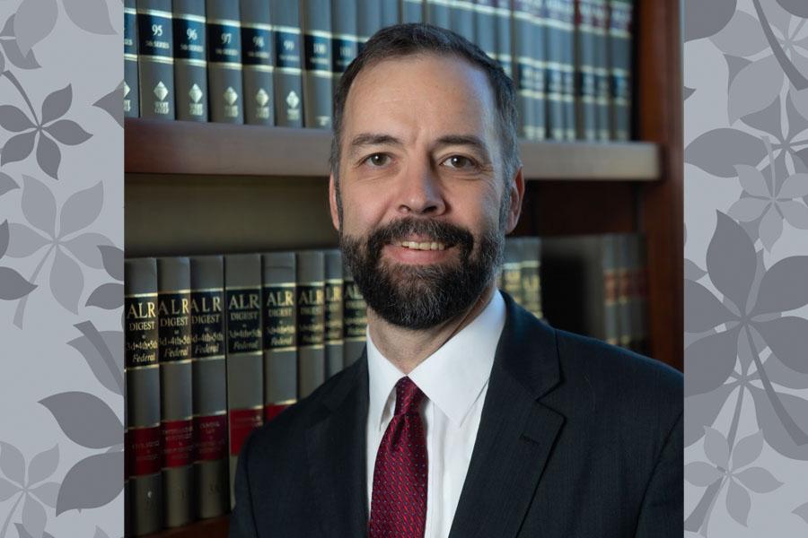 man in suit and tie, beard in front of law books