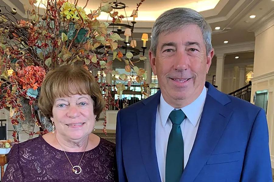 well dressed couple in front of fall floral bouquet