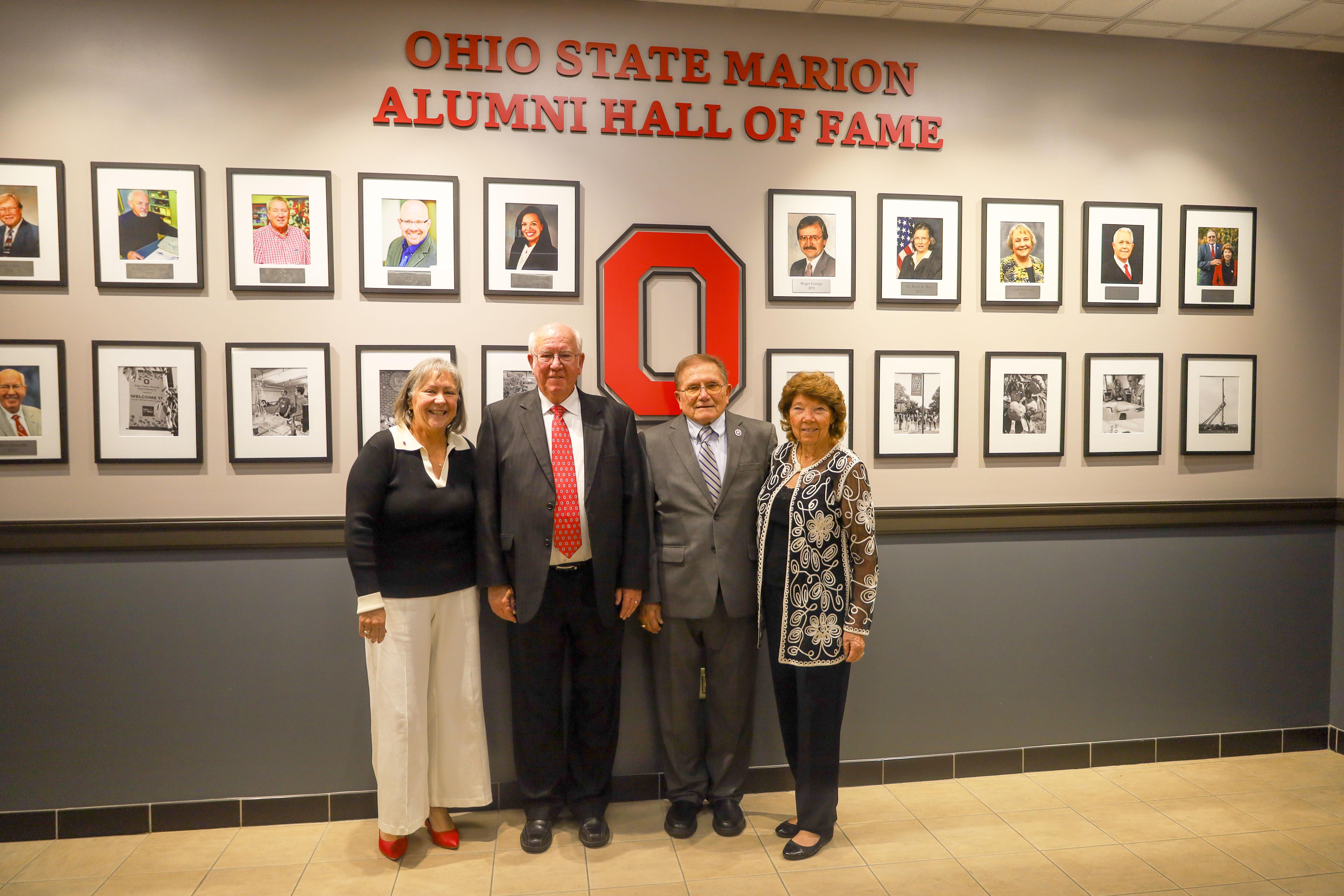 Four people in front of Hall of Fame photo collage