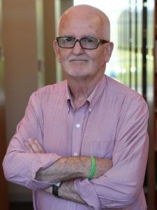 many in glasses pink shirt arms crossed