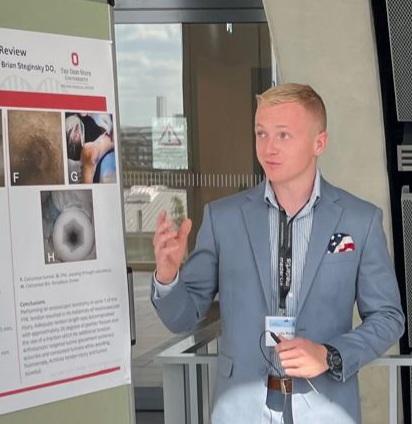 Young man pointing to research poster during presentatoin