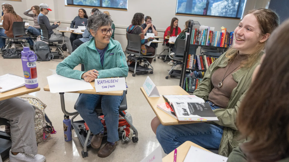 older woman in classroom desk with younger people