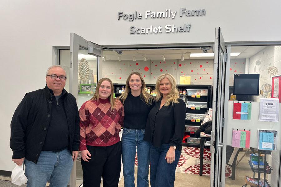 family of four poses in front of campus food pantry