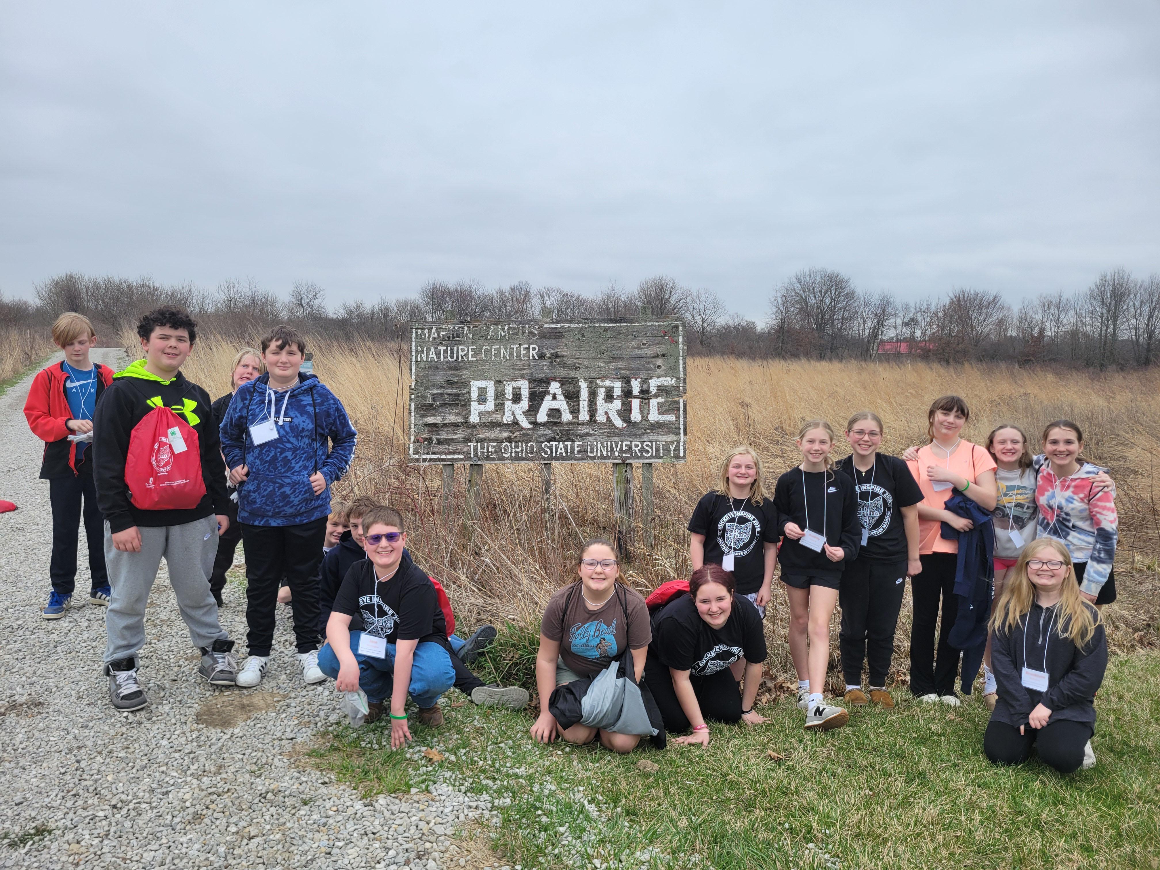 group of kids standing outside a prairie on a cloudy day