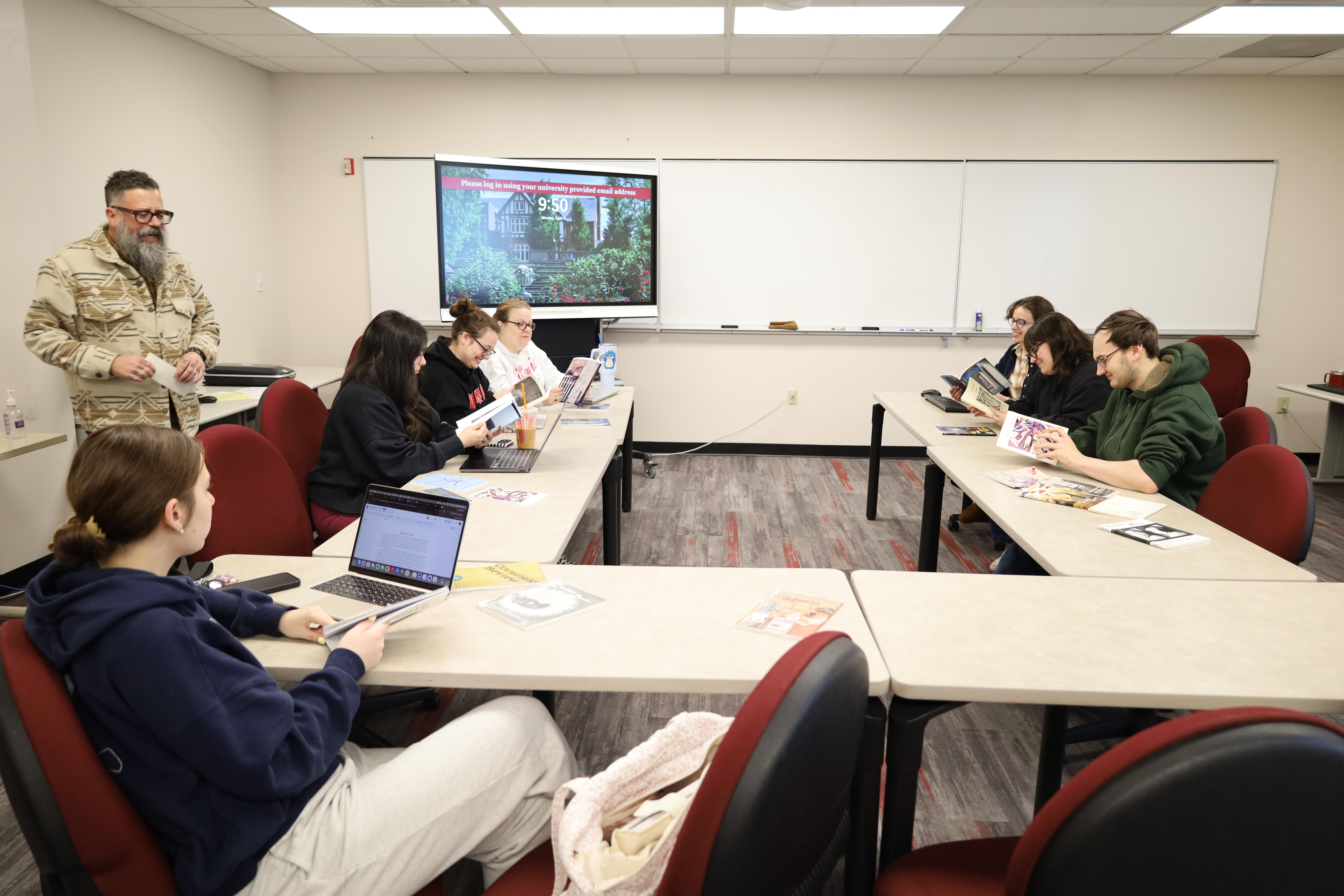 small group of students in classroom reviewing literary journal