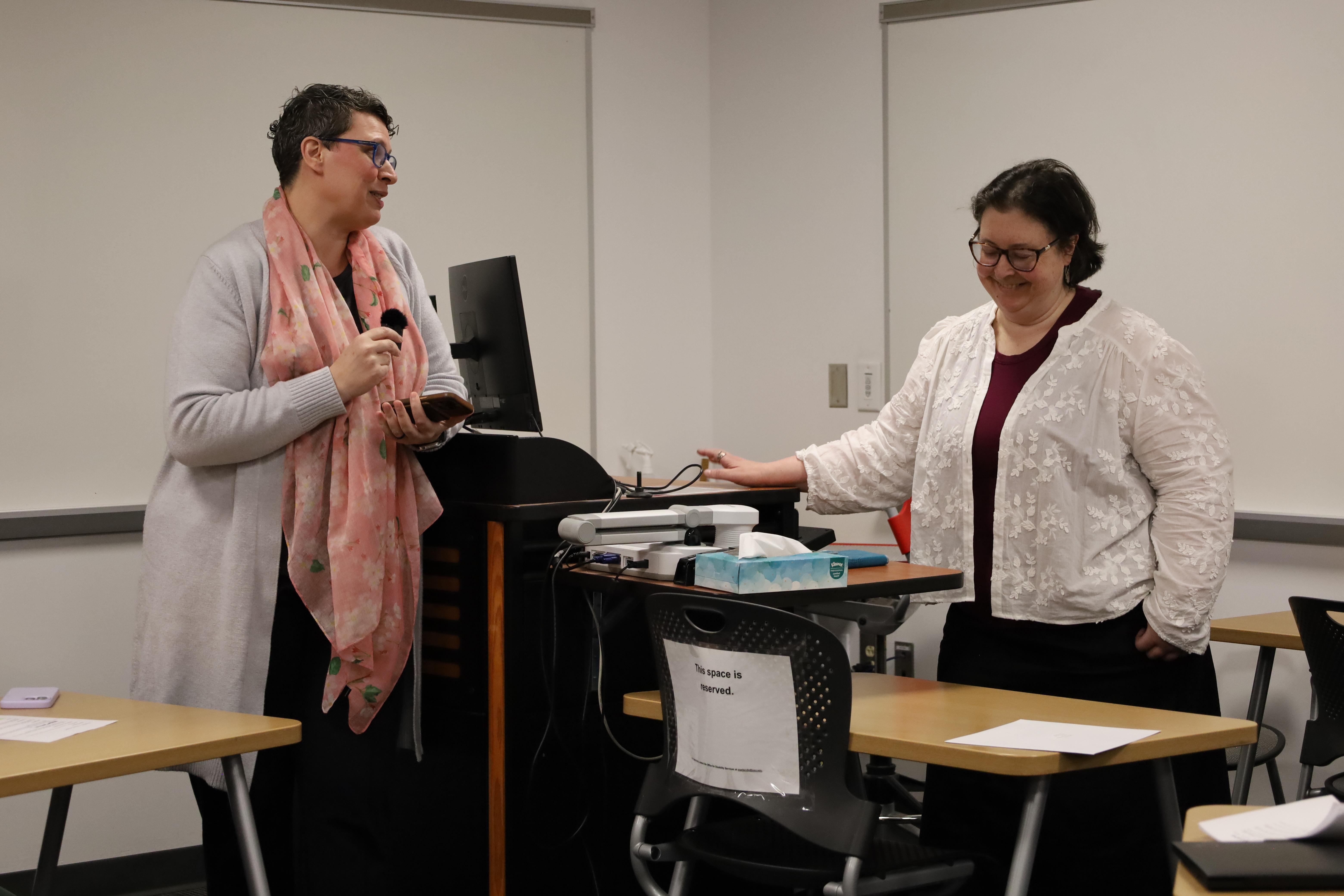 Woman holding small mic talks to teacher in classroom setting