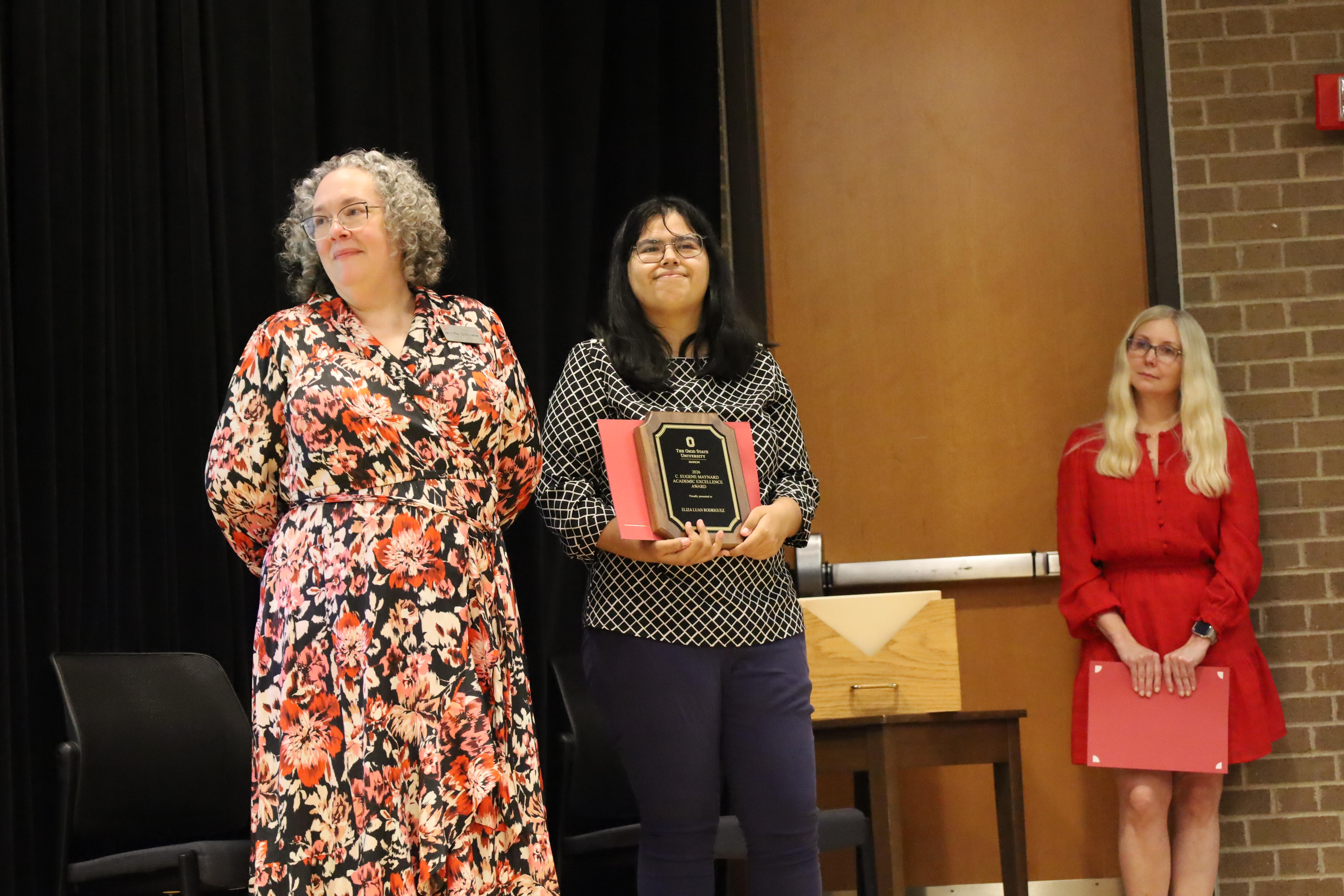 Three women on stage during awards presentation