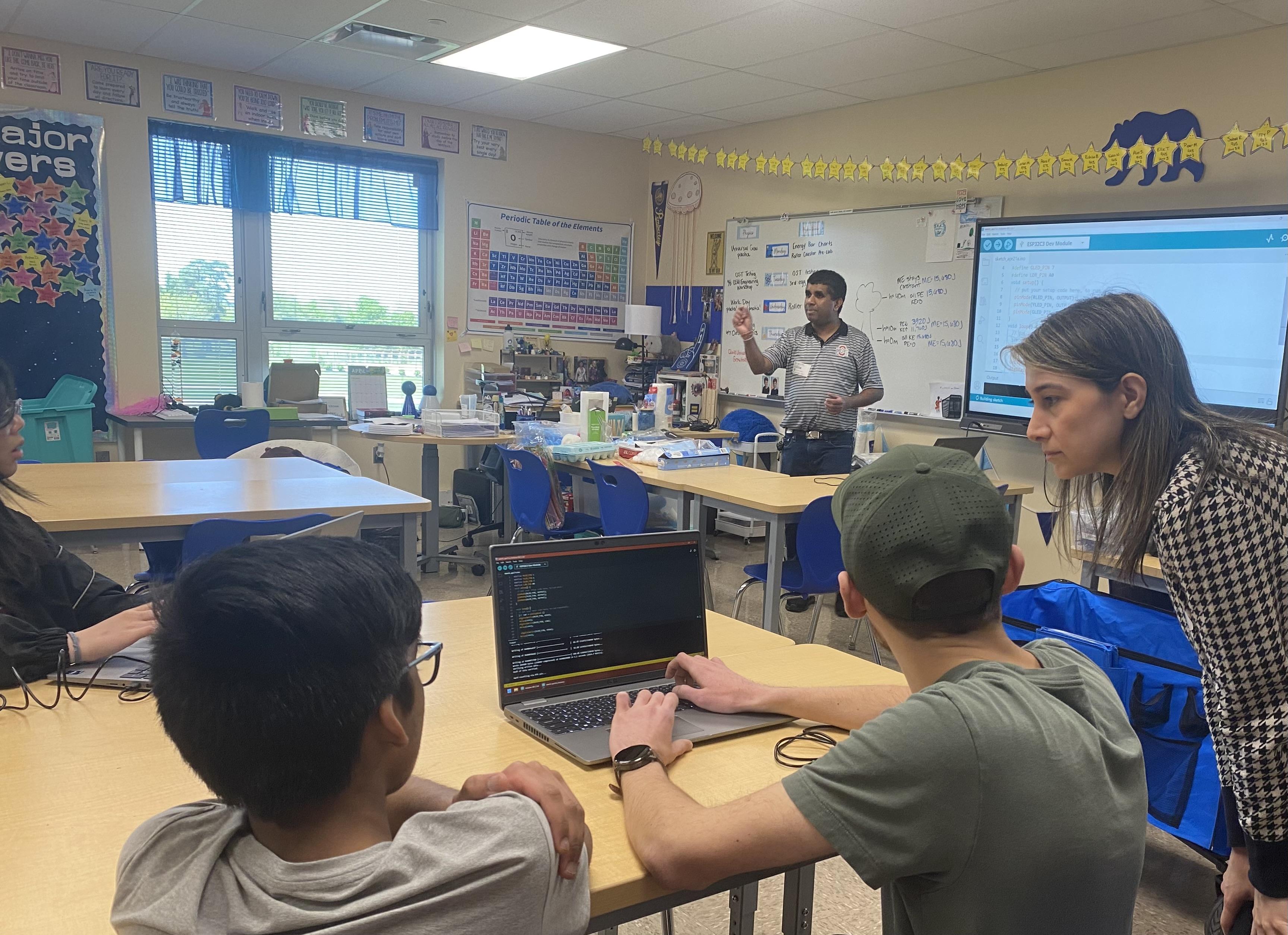 students in classroom learning STEM skills getting computer assistance