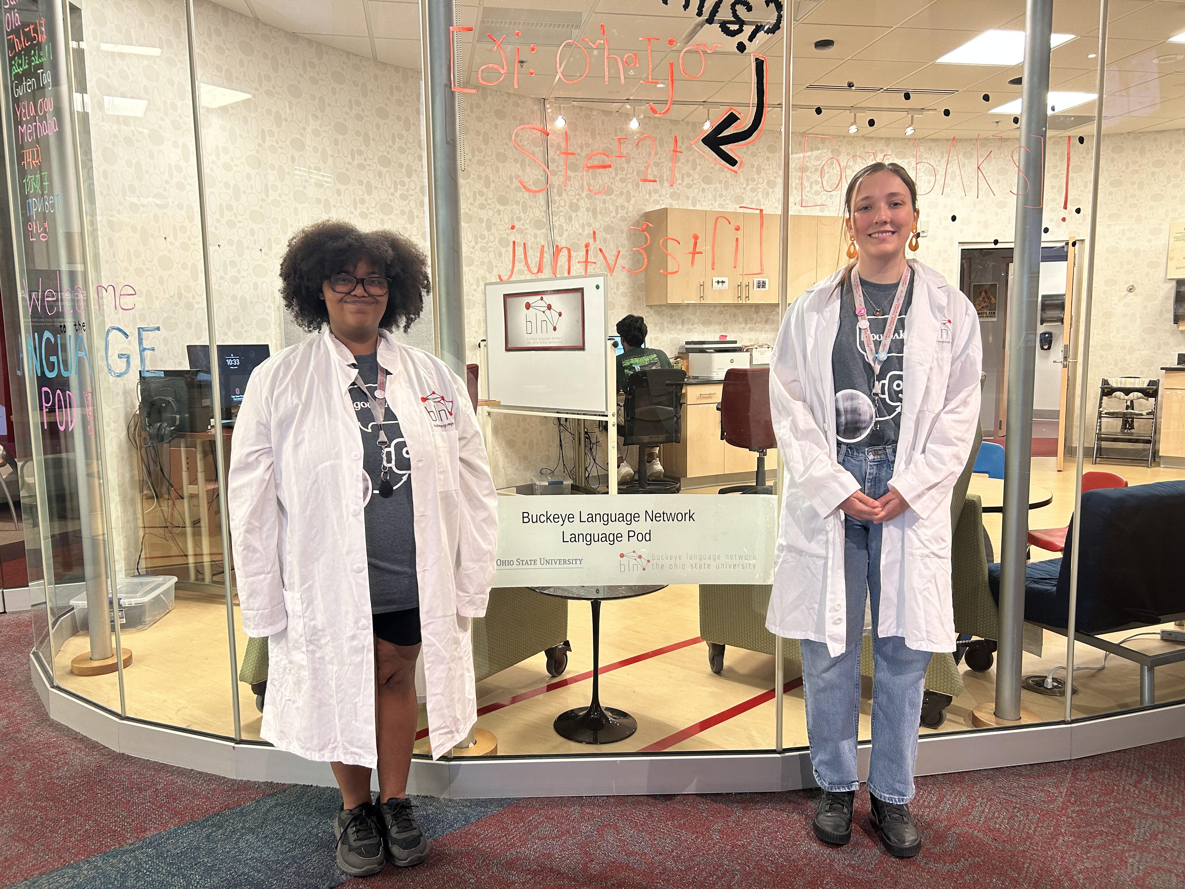students in lab jackets in front of glassed in pod