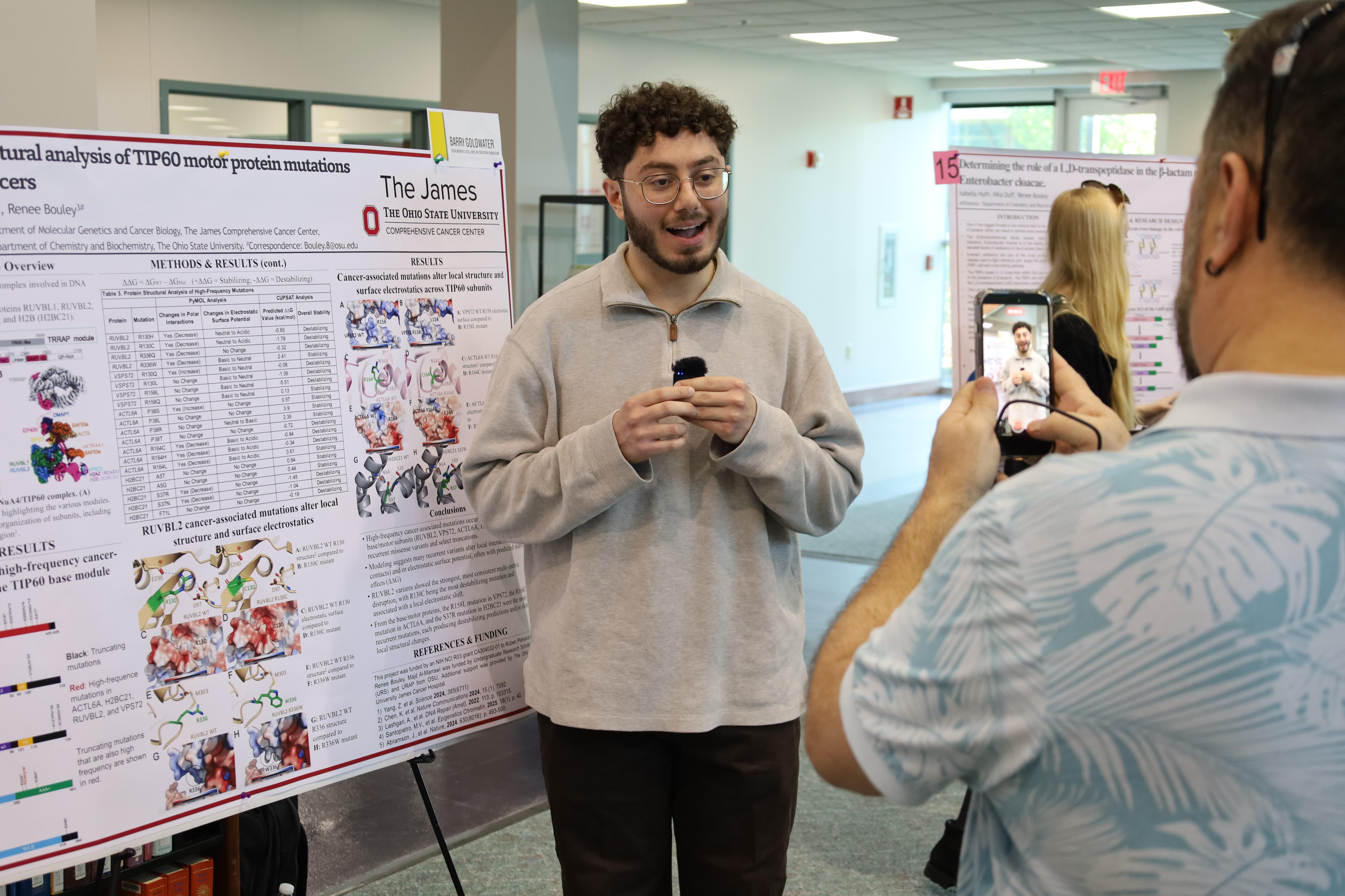 undergraduate researcher being interviewed during poster presentation