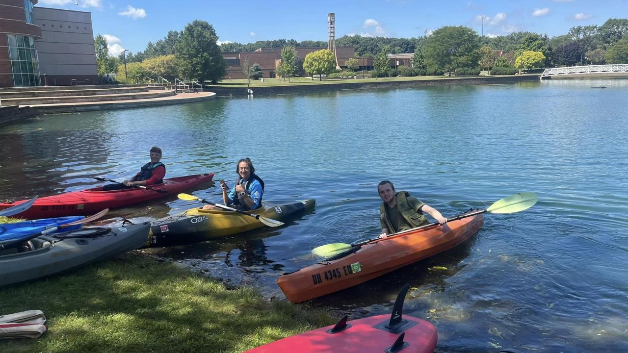 students prepare to ride canoes in the pond on campus