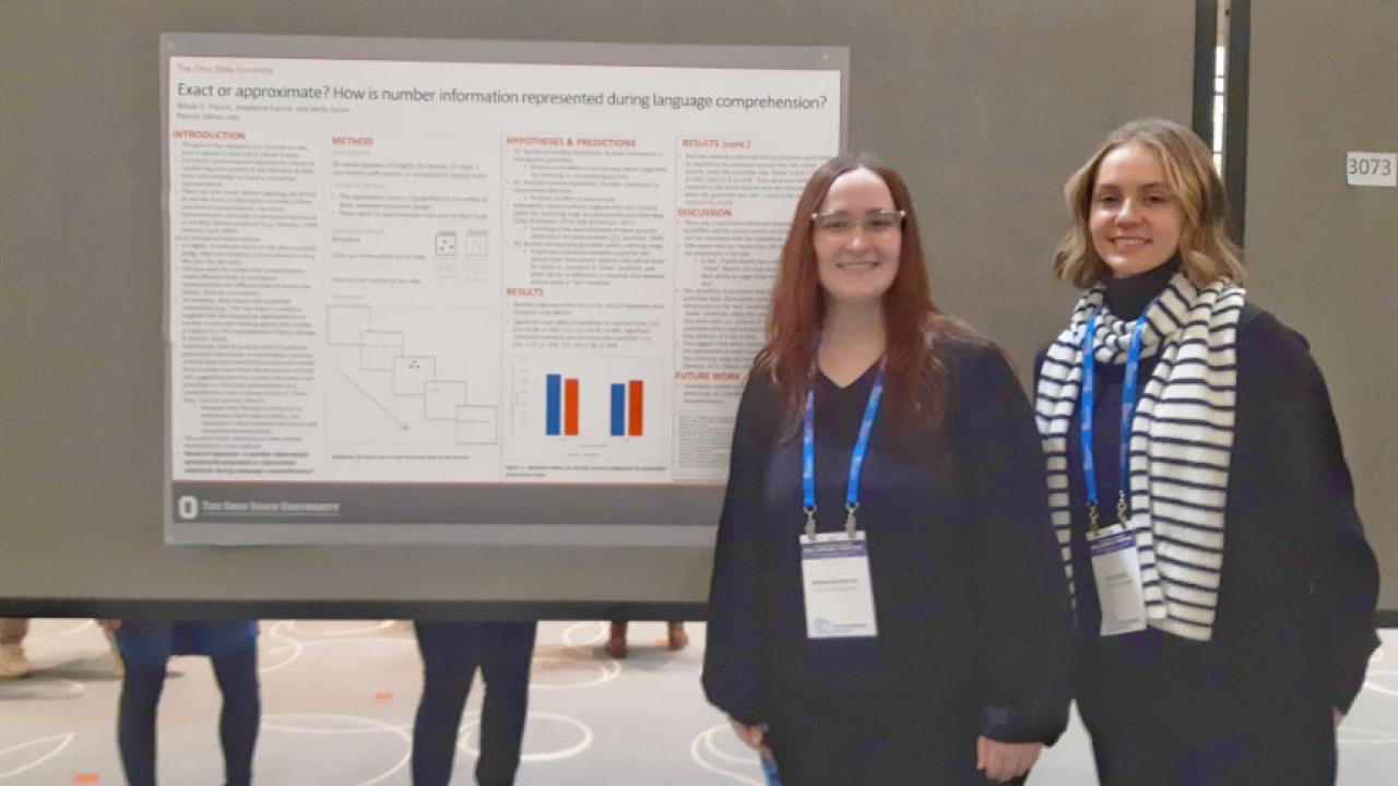 Two women standing next to research poster
