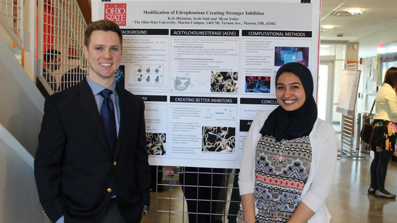 two students in front of their research poster