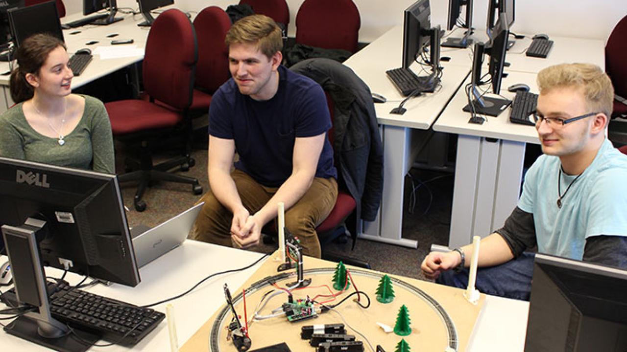 engineering students gathered in a classroom working on a model train