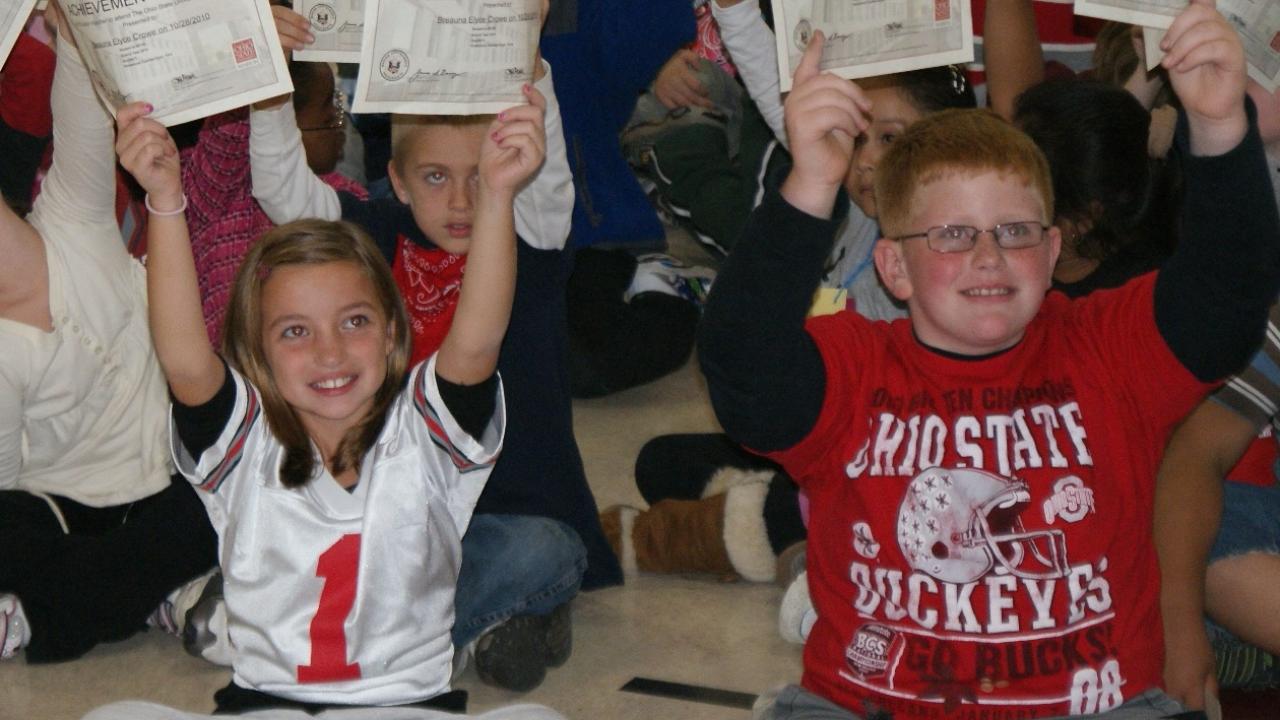 elementary children holding up certificates