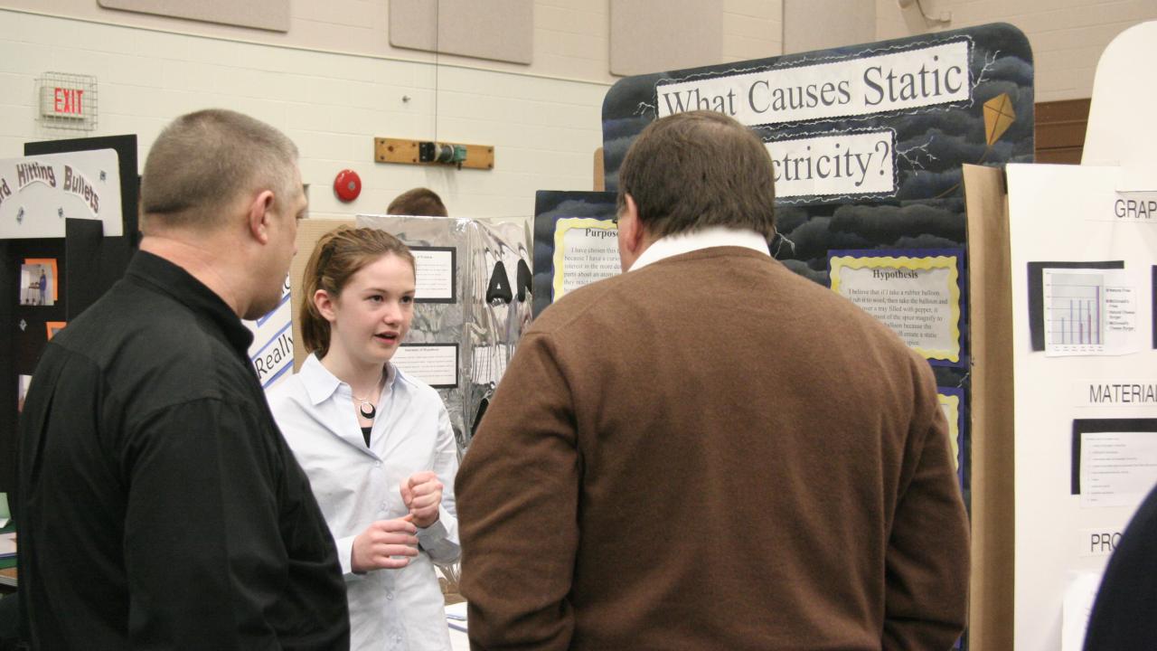 science fair judges speak to young woman about project