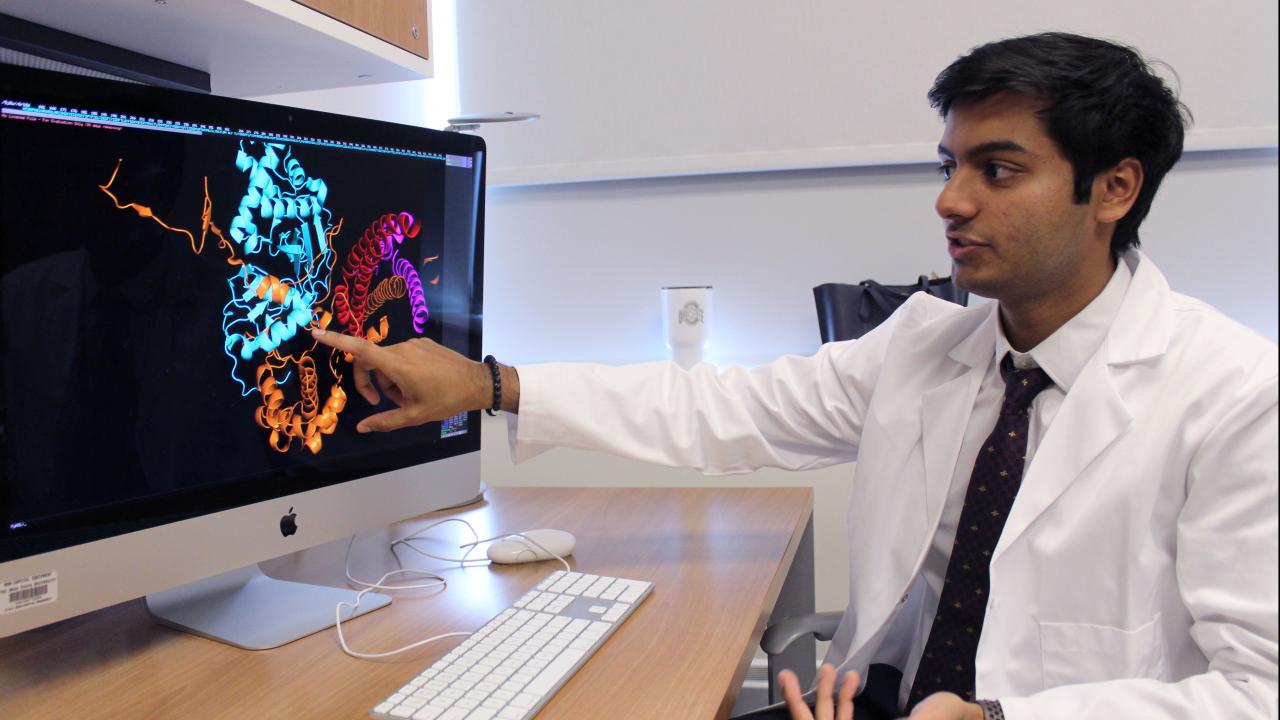 Biology major Shayaan Rasheed next to his research