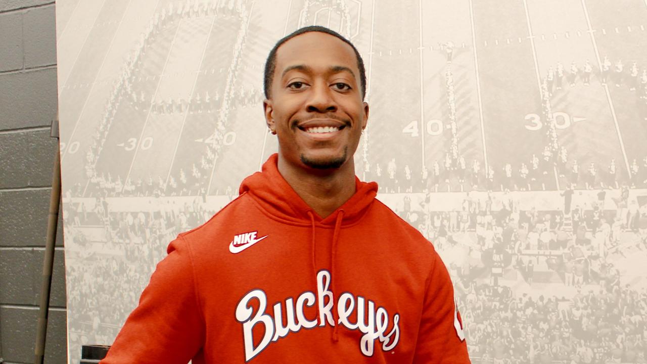 young man in red hoodie holding basketball and smiling