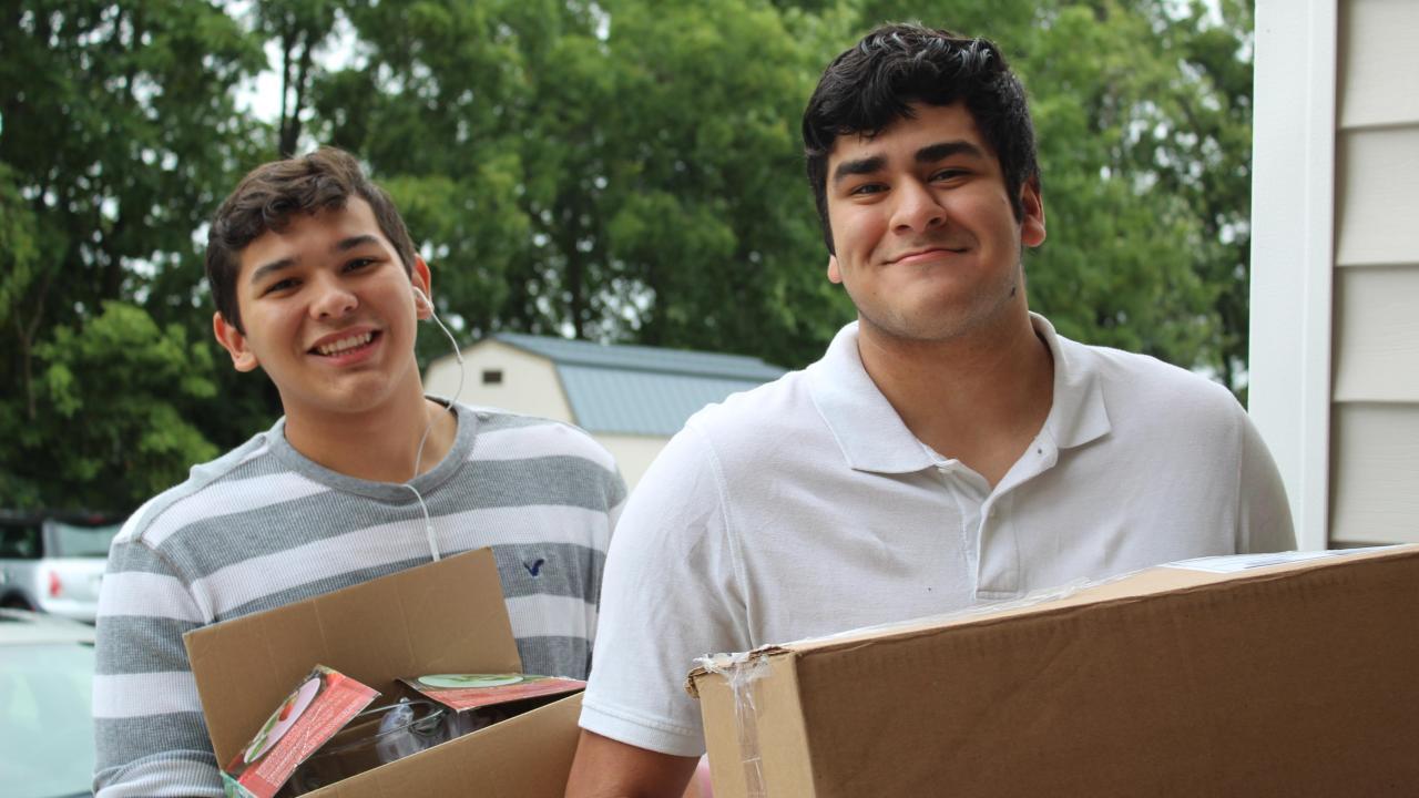 2 young men holding boxes