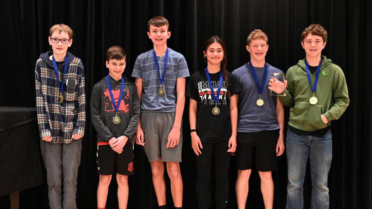 group of six middle school students with medals around neck