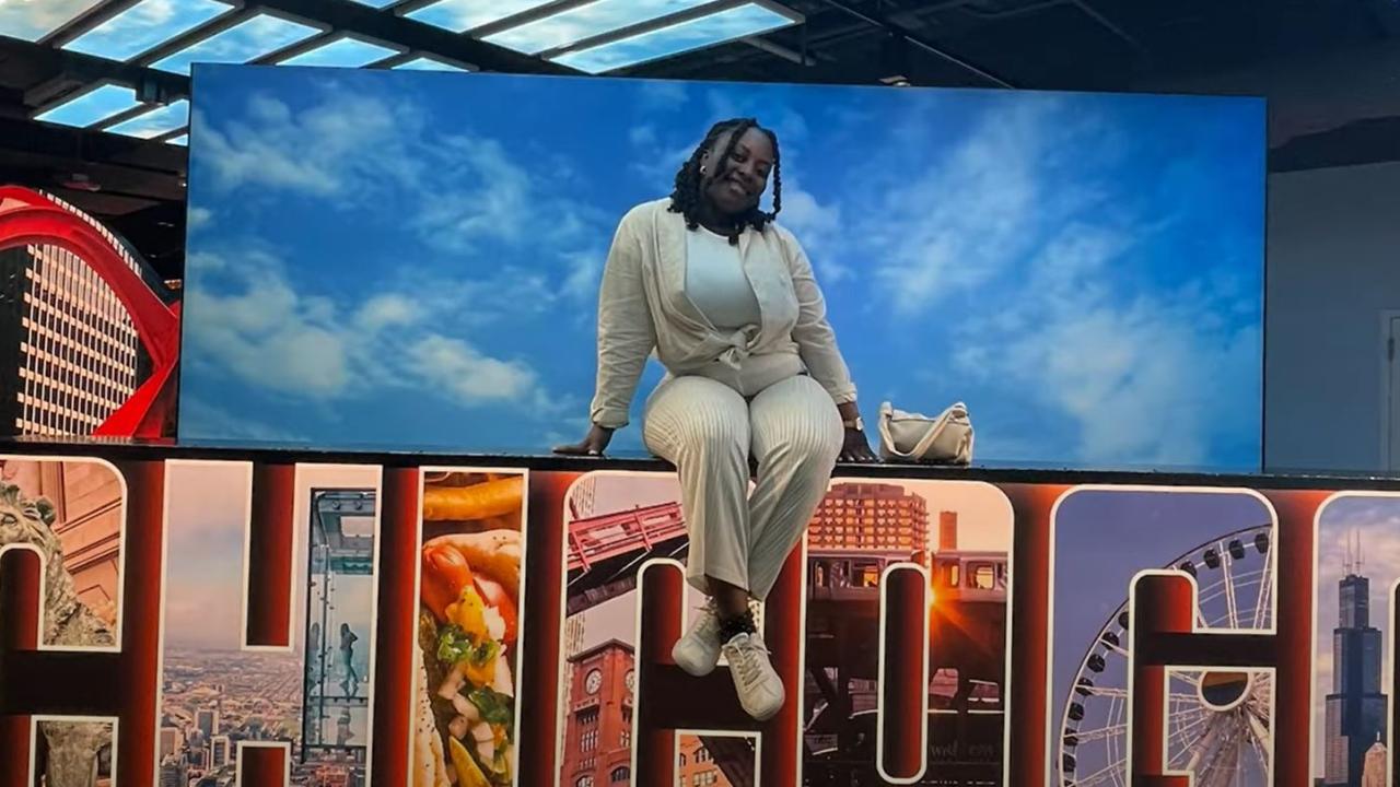 Young black woman sitting on Chicago sign