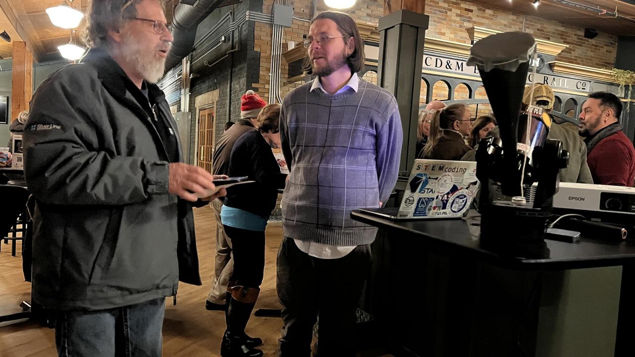 two men engaged in conversation at busy restaurant