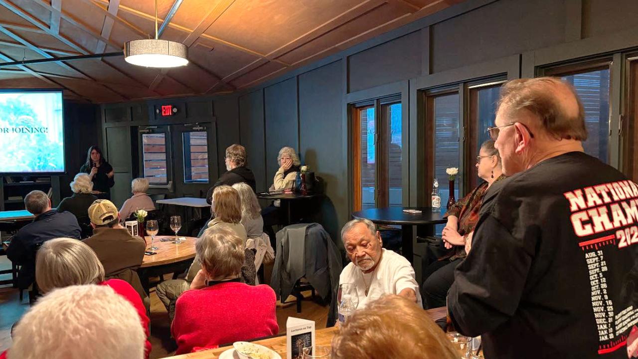 man asking question into a mic in crowded restaurant