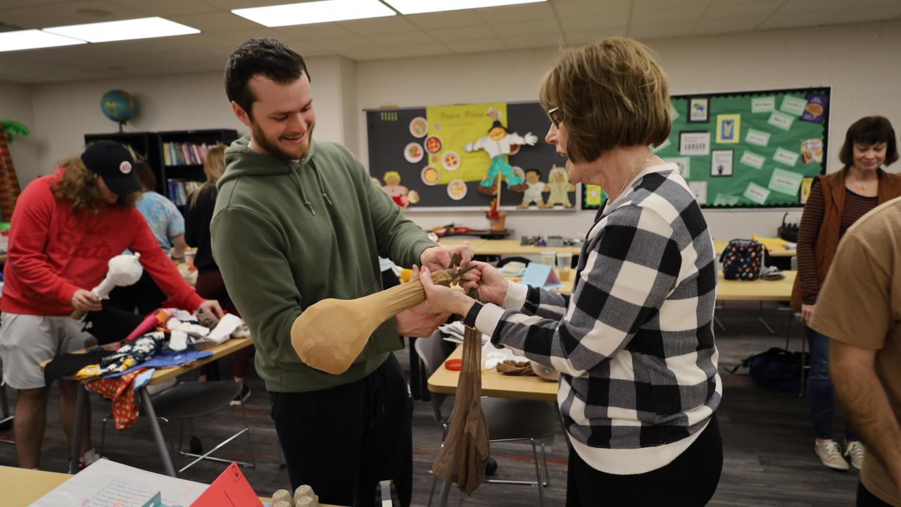 an instructor and student build a sock puppet together