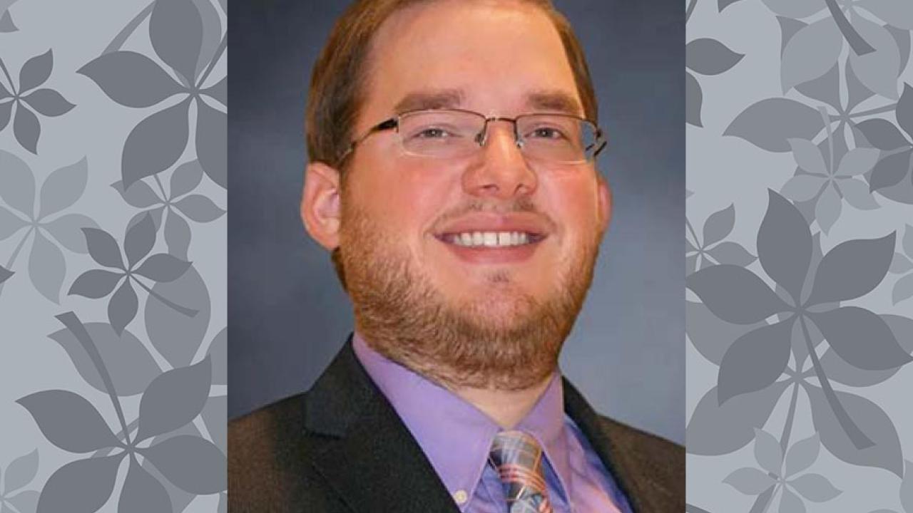 man with glasses suit purple shirt & tie