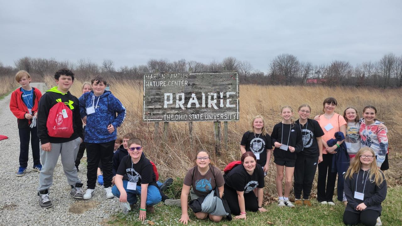 children from a youth camp posing by the prairie sign