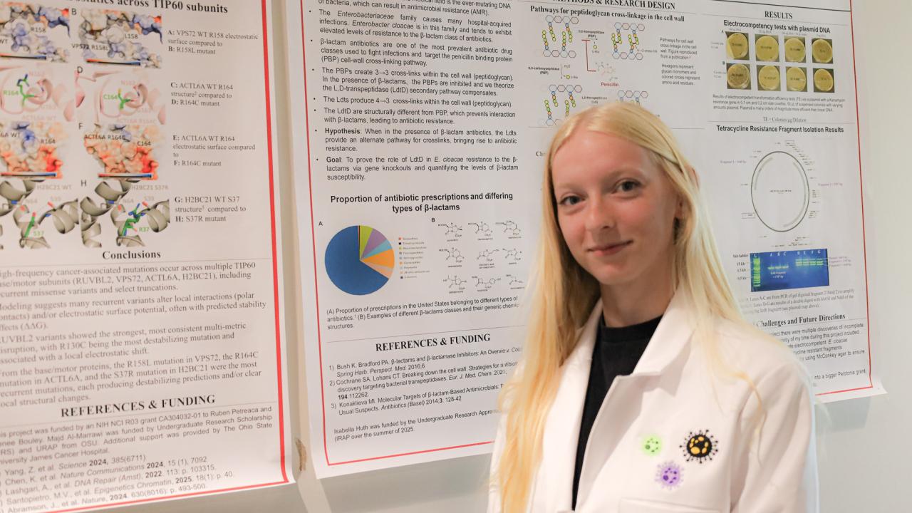 woman in lab coat in front of research posters